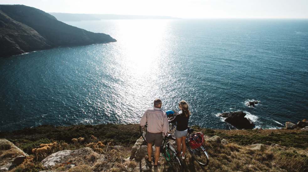 Visit Jersey couple with bikes looking at sea